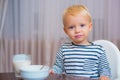 Toddler having snack at home. Boy cute baby eating breakfast. Child eat porridge. Kid cute boy blue eyes sit at table