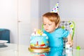 Toddler in high chair blow candles birthday cake