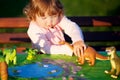 Toddler kid playing with a toy dinosaur. Royalty Free Stock Photo