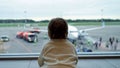 Toddler looking at plane with people through large window