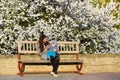 Toddler with mom on the background of flowering trees. little baby on hands of mother. woman playing with child outside in Royalty Free Stock Photo