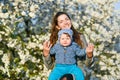 Toddler with mom on the background of flowering trees. little baby on hands of mother. woman playing with child outside in Royalty Free Stock Photo