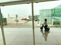 Toddler observing the planes at the airport, while riding his motorbike.