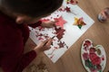 Toddler painting wooden decorations red