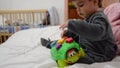 Toddler in pajamas playing with turtle education toy on the bad with newborn baby in the crib behind early development