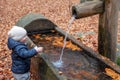 Toddler playing at a forrest fountain in autumn