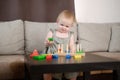 Toddler plays with a wooden educational toy while sitting on the sofa at home. Montessori games for child development Royalty Free Stock Photo