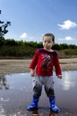 Toddler posing in a puddle with his new boots Royalty Free Stock Photo