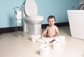 Toddler ripping up toilet paper in bathroom