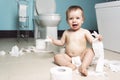 Toddler ripping up toilet paper in bathroom