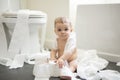 Toddler ripping up toilet paper in bathroom