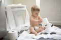 Toddler ripping up toilet paper in bathroom