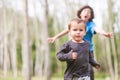 Toddler running towards the camera with an older child running behind him