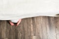 Toddler scared and climb up under the bed. Small child`s feet on floor