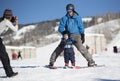 Toddler Screams with Delight as he Learns to Ski with Dad While Mom takes a Photo