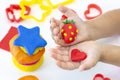 Toddler sculpts from colored plasticine on a white table.