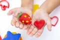 Toddler sculpts from colored plasticine on a white table.