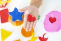 Toddler sculpts from colored plasticine on a white table.