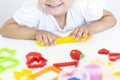 Toddler sculpts from colored plasticine on a white table.