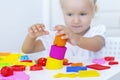 Toddler sculpts from colored plasticine on a white table.