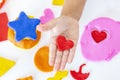 Toddler sculpts from colored plasticine on a white table.