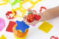 Toddler sculpts from colored plasticine on a white table.