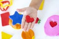 Toddler sculpts from colored plasticine on a white table.