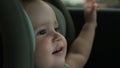 Toddler sits in child car safety seat and looks out window