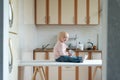 Toddler sits on kitchen table and waits for mom. Home breakfast