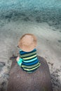 Toddler sitting on small stone pier with shallow sea water Royalty Free Stock Photo