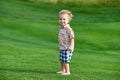 Toddler standing at the green golf course at sunny day