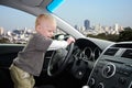 Child Pretends to Drive Car in Big City