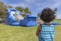 A toddler stands very still watching a bounce house inflate