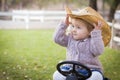Toddler Wearing Cowboy Hat and Playing on Toy Tractor Outside Royalty Free Stock Photo