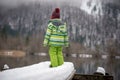 Toddler in winter suit standing on snowy pier at a lake
