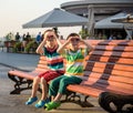 Toddlers boy and his sibling brother sitting on a bench by the c