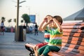 Toddlers boy and his sibling brother sitting on a bench by the c