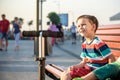 Toddlers boy and his sibling brother sitting on a bench by the c