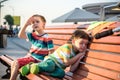 Toddlers boy and his sibling brother sitting on a bench by the c