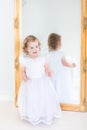 Toddlger girl trying on white dress in front of mirror