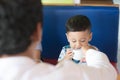 Asian todler eating sweet cake and his family at cafe