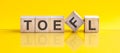 toefl word is made of wooden building blocks lying on the yellow table, concept