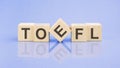 TOEFL - word is written on wooden cubes on a blue background. close-up of wooden elements