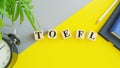 TOEFL - words from wooden blocks with letters, The Test of English as a Foreign Language, TOEFL concept, yellow background