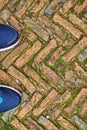 Toes of modern training shoes standing on old cobble stones in a Royalty Free Stock Photo