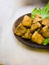 Tofu filled with meatballs and lettuce on wooden plate