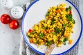 Tofu scramble with vegetables in a white plate, top view. Vegan Alternative fried eggs Royalty Free Stock Photo