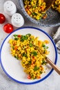 Tofu scramble with vegetables in a white plate, top view. Vegan Alternative fried eggs Royalty Free Stock Photo
