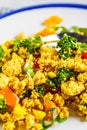 Tofu scramble with vegetables in a white plate. Vegan Alternative fried eggs