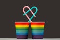 Together forever. Two LGBT color paper cups with pink and blue heart shaped cocktail tubes. The concept of love of people of